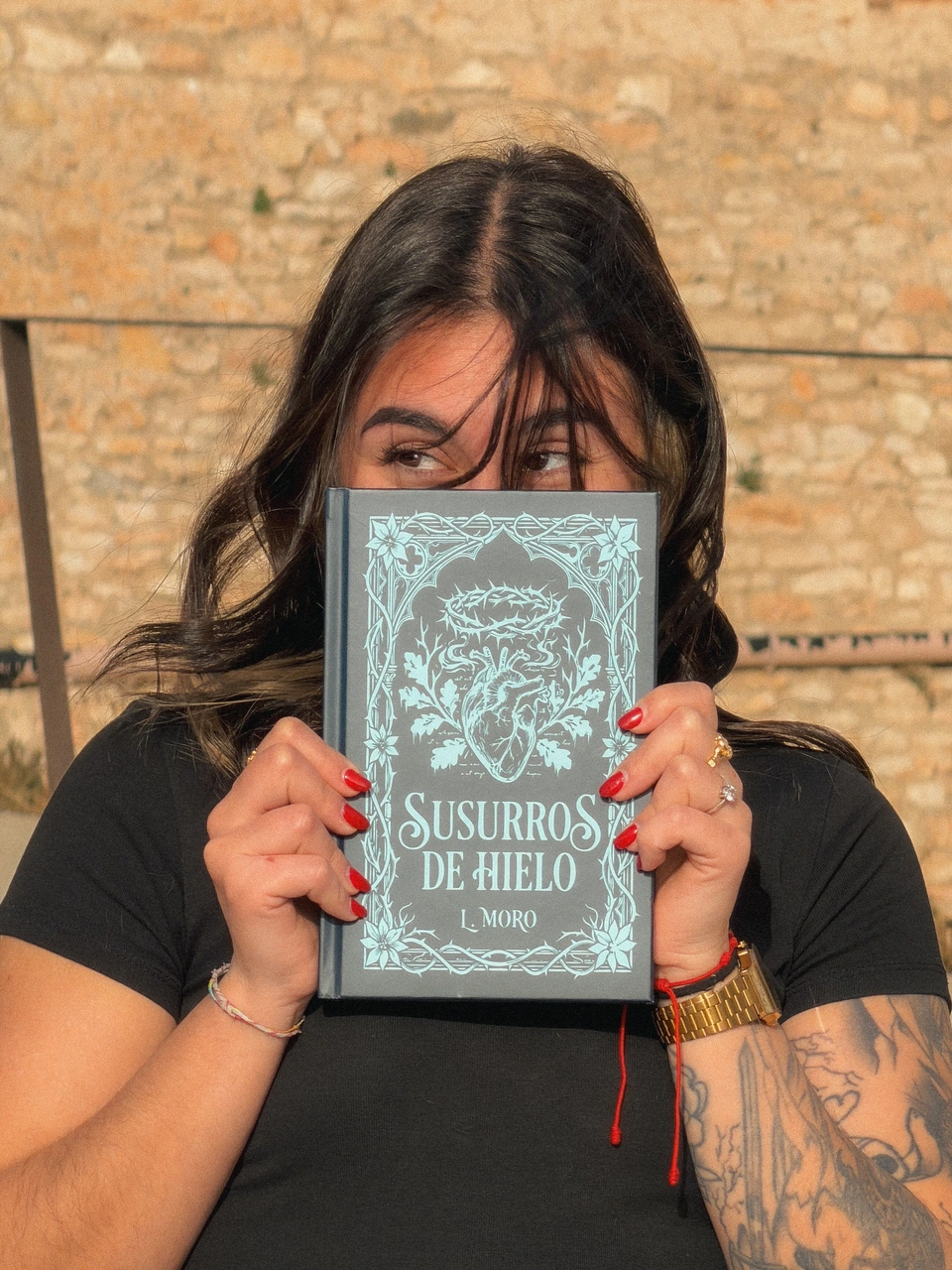 Portrait of a woman holding Susurros de Hielo in front of her face.